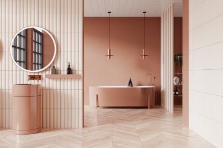 Moderner Badezimmerbereich mit rosa Wänden, runder Spiegel und freistehender Badewanne.