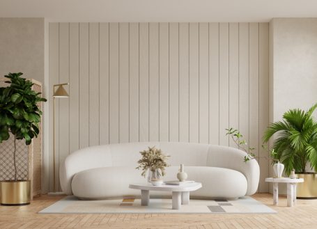 Helles Wohnzimmer mit einer weißen Couch, Pflanzen und einem minimalistischen Beistelltisch.
