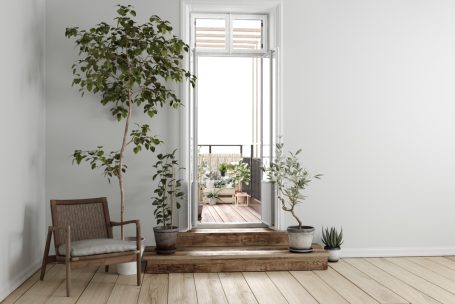 Helle Innenansicht mit einer Tür zu einem Balkon, umgeben von Pflanzen und einem Stuhl.