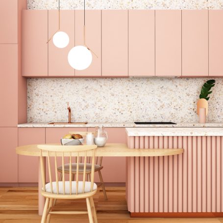 Moderne Küche in Rosa mit Holzdetails und runder Esstisch. Elegante Pendelleuchten.